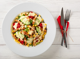 Caesar style salad with grilled chicken breast and fresh vegetables on a white wooden table. Top view 
