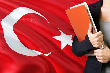 Learning Turkish language concept. Young woman standing with the Turkey flag in the background....