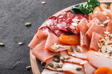 Antipasto platter cold meat, prosciutto, slices ham, beef jerky, salami, meat and nuts on cutting...
