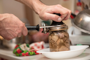 Man is canning pork stew, process close-up. Homemade cooking with a traditional recipe, Ukrainian cuisine