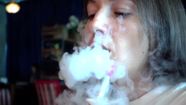 The girl smokes a smoky hookah. Slow motion of thick smoke hookah