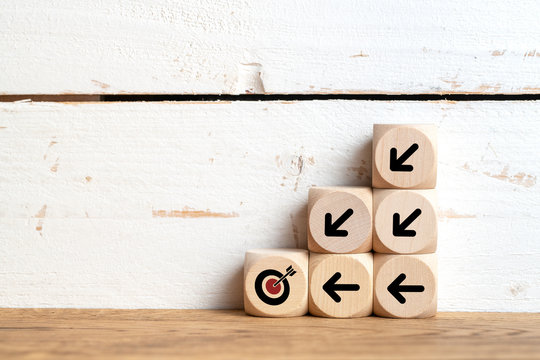 stacked cubes on wooden background with a target symbol and arrows pointing to this target symbolizing to organize a team to a common goal