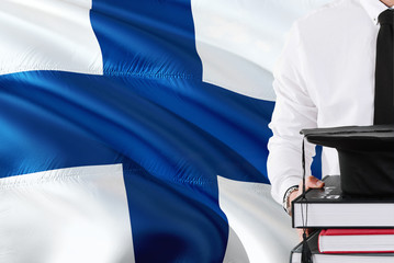 Successful Finnish student education concept. Holding books and graduation cap over Finland flag...
