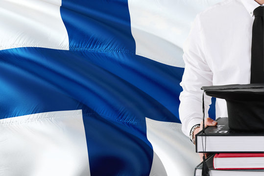 Successful Finnish Student Education Concept. Holding Books And Graduation Cap Over Finland Flag Background.