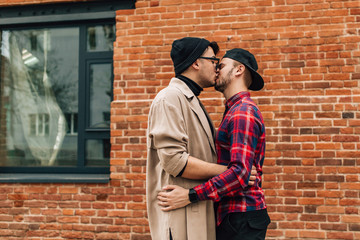 Fototapeta na wymiar Gay couple kissing on the lips while standing outdoors. Concepts of same-sex marriage in the world. Kiss two men