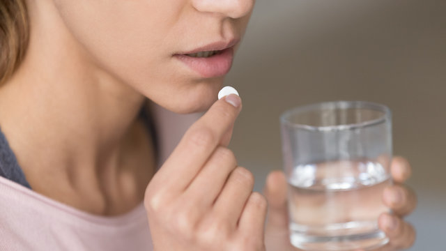 Close up image woman holding pill and glass of water
