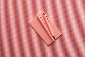 minimalistic background with pens and notebook on textured pink