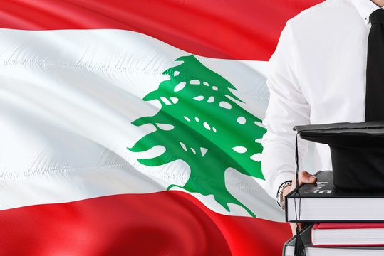 Successful Lebanese student education concept. Holding books and graduation cap over Lebanon flag background.