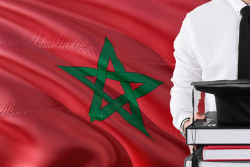 Successful Moroccan student education concept. Holding books and graduation cap over Morocco flag...