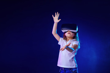 Girl 7 y.o. experiencing VR headset game on colorful background. Child using a gaming gadget for virtual reality. Futuristic goggles at young age. Virtual technology © zamuruev