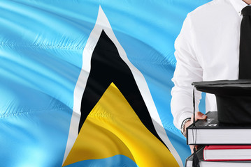 Successful student education concept. Holding books and graduation cap over Saint Lucia flag background.