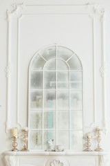 Arch window in a room decorated for celebrating Christmas. Luxury interior in white colors. Frozen mirror