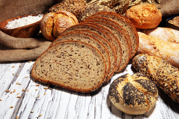 Assortment of baked bread and bread rolls on rustic white bakery table background