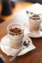 Layered vanilla-chocolate mousse with topping on a wooden rustic table