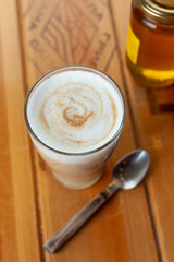 Glass of spicy tea latte on a rustic table served with honey