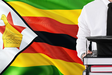 Successful Zimbabwean student education concept. Holding books and graduation cap over Zimbabwe flag background.