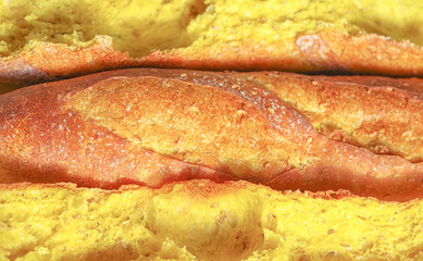 Freshly baked bread. Close up of yellow French baguette with turmeric spice and sesame.