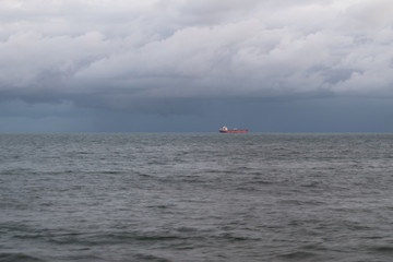 Cargo ship out at sea under a rain cloud