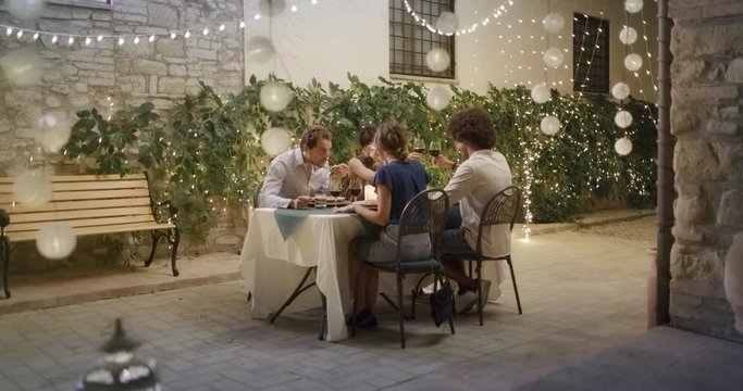 Four people, two couples happy talking and eating during a romantic gourmet dinner or lunch.Approaching wide shot. Friends italian trip in Umbria.4k slow motion