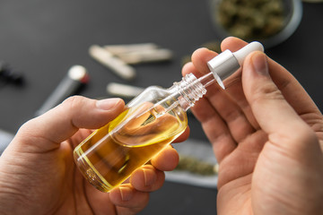 medical marijuana concept, hemp product, CBD cannabis OIL. Hand holding bottle of Cannabis oil in...