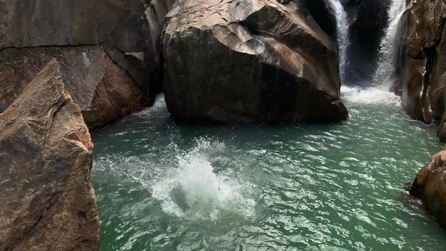 Guy jumping from rocky cliff on waterfall in Vietnam