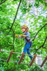 Naklejka na ściany i meble Small boy enjoy childhood years. Safe Climbing extreme sport with helmet. Child concept. Happy child climbing in the trees.