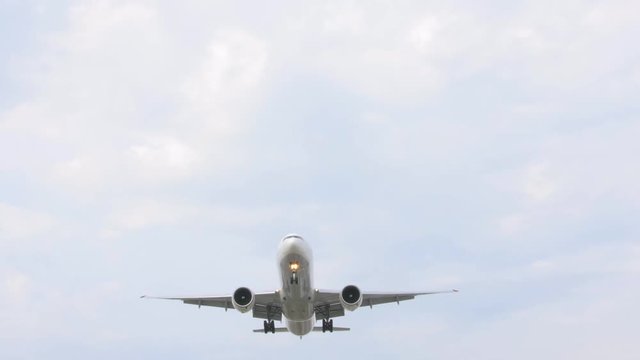 Large passenger airplane landing against beautiful clear sky. Commercial airplane flying directly over camera.