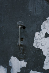 Natural water corrosion texture. Old rusty slim handle on a retro door. Peeling paint on a dark blue and gray door.