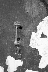  Old rusty slim handle on a retro door. Old door knob on vintage texture. Peeling paint. Vertical black and white photography