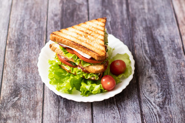 Sandwich with cheese, tomato, cucumber, sausage and salad on wooden background. Horizontal orientation