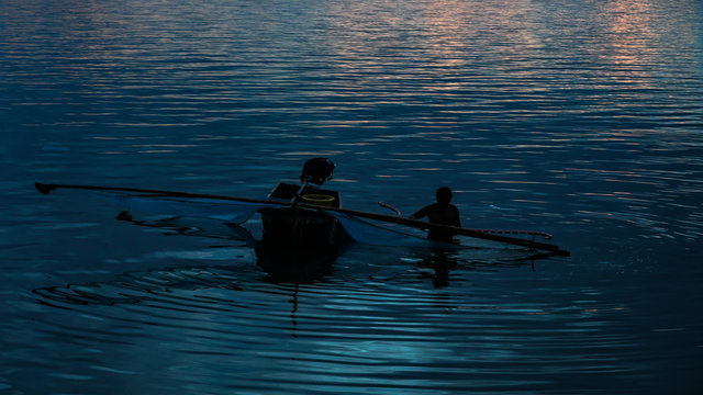 Silhouette of fishermen catching fish in the sea at sunset