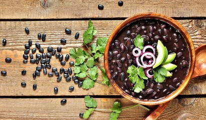 thick black bean soup or stew. Latin American or Mexican cuisine. stewed black beans served with avocado and red onion and cilantro. place for text. top view.
