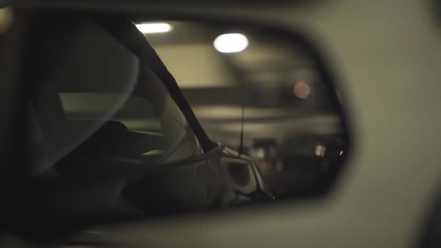 Shot of a side mirror of a Ford Mustang in movement during night time.