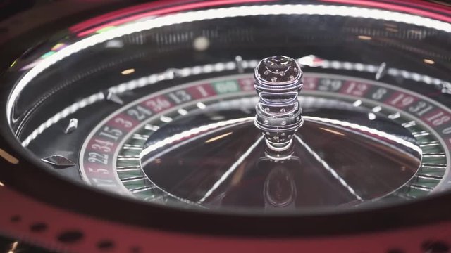 Panning shot of poker coins and card playing table at a casino.