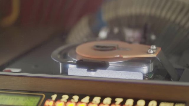 Close-up shot of a retro jukebox song player real size playing a compact disk inside.