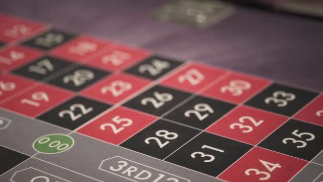 Panning shot of numbers on a table of a gambling roulette wheel at a casino.