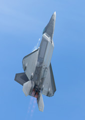 F-22 Raptor in a  high G climb in beautiful light , with condensation trails forming  around the...