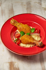 Chicken legs on the side with mashed potatoes. Light wooden background. Restaurant menu