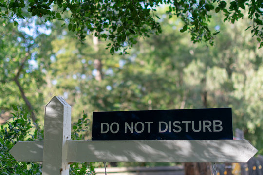 Do not disturb warning sign in rural area with blurred green trees in background - Powered by Adobe