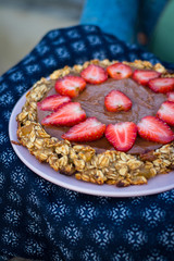 Hands holds delicious strawberry chocolate cake, baked tasty  homemade pie on plate with oatmeal. Organic sweet vegan dessert with fruits. Healthy food
