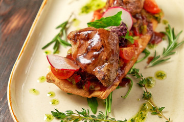 Grilled meat on pita bread on a bright oval plate. Dark wooden background. Restaurant menu