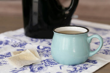 A cup of green tea on a coffee table with black kettle on the background.