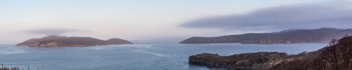 Seascape with capes and the island, over which hung a thunderstorm. Image of landscape and weather phenomena. Panoramic landscape