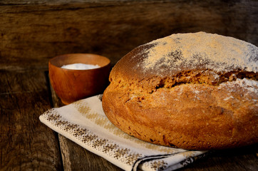 Rustic bread, towel the salt on a wooden old table.