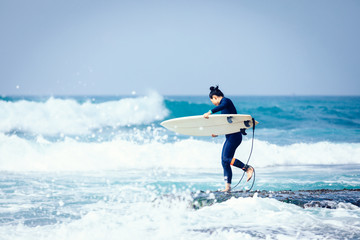 Woman surfer with surfboard going to surf the big waves