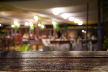 Empty wood table top and blur of night pub or restaurant background/selective focus.