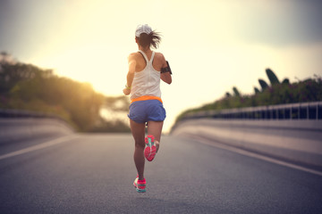 young fitness asian woman runner running on city road