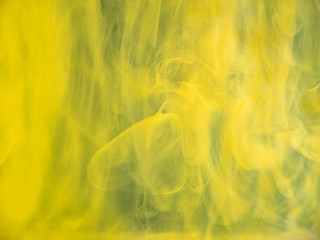 Droplets of acrylic paint dissolving into water, abstract background. Close up view. Blurred background. Selective soft focus. Yellow ink transforming in liquid, abstract pattern