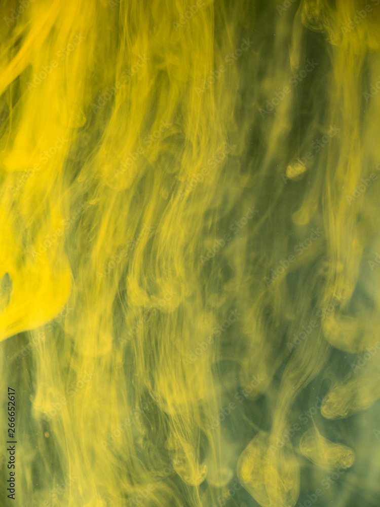 Poster drops of yellow acrylic ink mixing with liquid, close up view. blurred background. abstract acrylic 