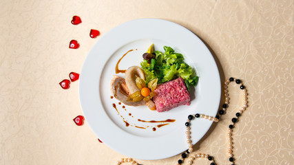 Restaurant dish of fish and beetroot salad in a white plate in the interior top view.